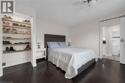 Bedroom with a barn door, dark wood-type flooring, and a ceiling fan -