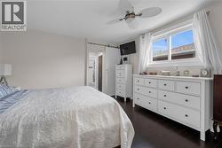Bedroom featuring a barn door, dark wood-style flooring, and ceiling fan -