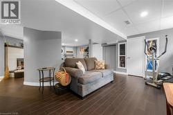 Living room featuring a paneled ceiling, dark wood-style floors, and a tile fireplace -
