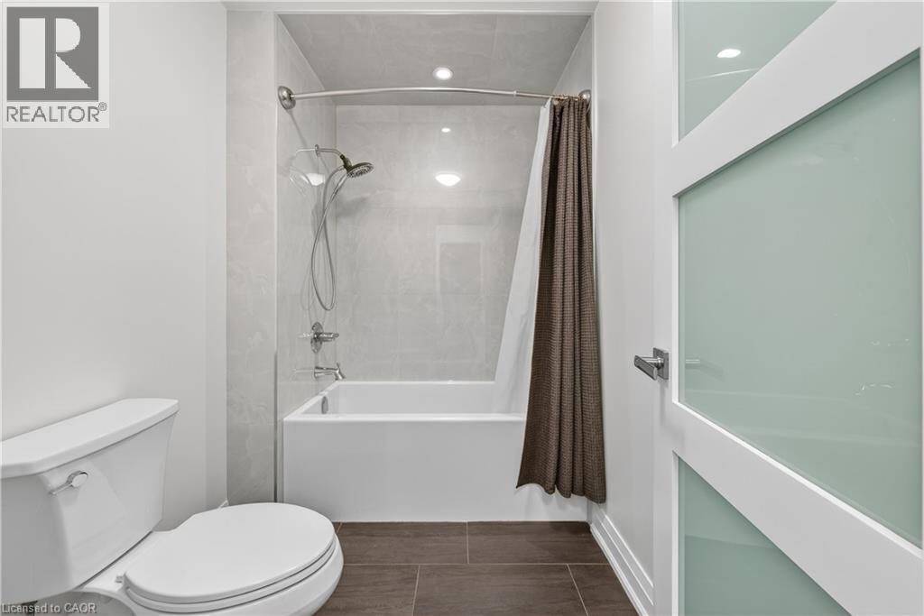 Bathroom featuring shower / bath combo and dark tile patterned floors - 18 David Avenue, Hamilton, ON - Indoor Photo Showing Bathroom