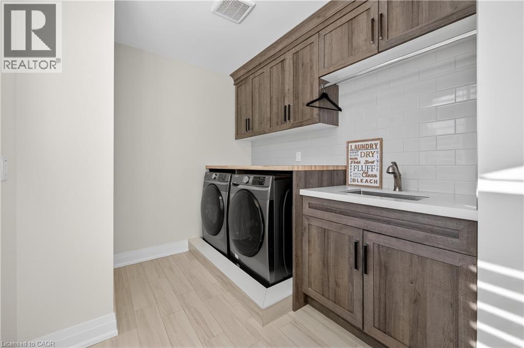 Washroom with cabinet space, independent washer and dryer, and light wood-type flooring - 18 David Avenue, Hamilton, ON - Indoor Photo Showing Laundry Room