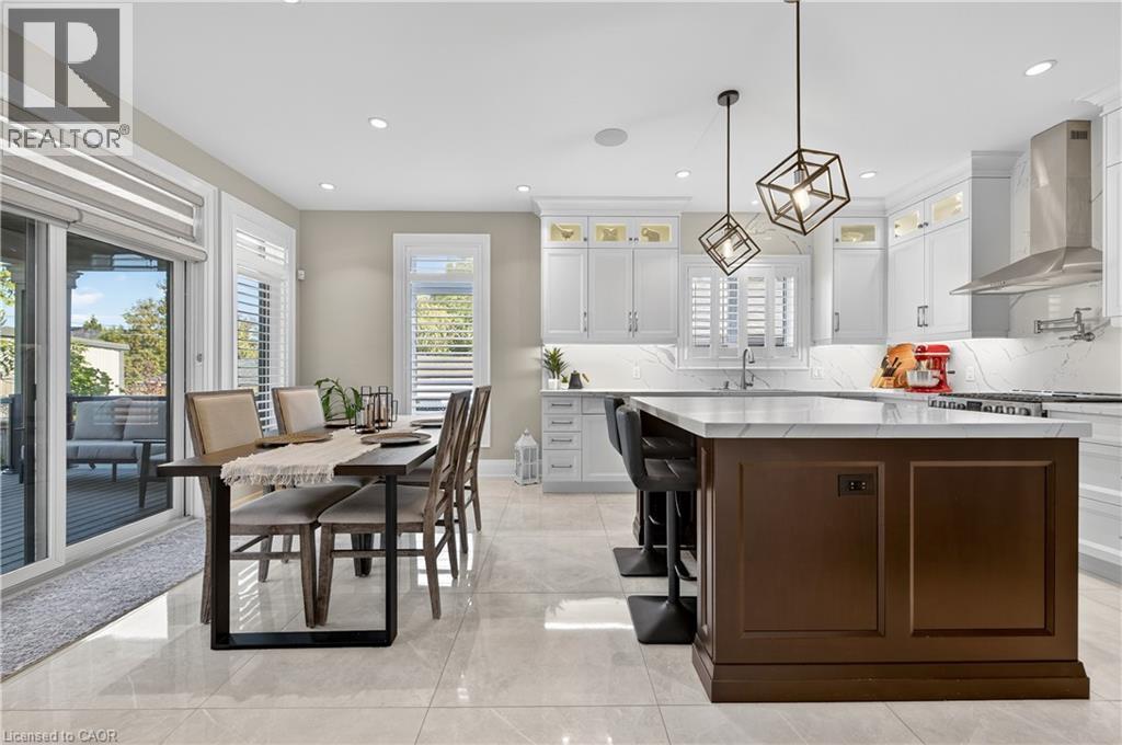 Kitchen featuring white cabinetry, glass insert cabinets, dark brown cabinets, tasteful backsplash, and wall chimney exhaust hood - 18 David Avenue, Hamilton, ON - Indoor Photo Showing Other Room