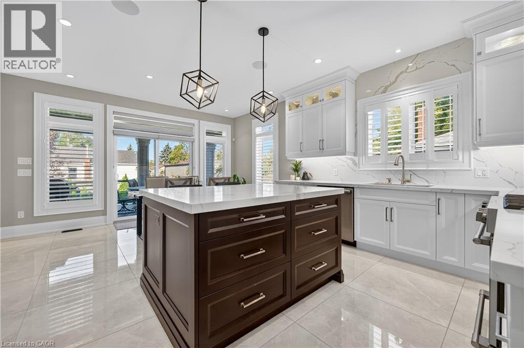 Kitchen with white cabinets, dark brown cabinetry, pendant lighting, light stone counters, and plenty of natural light - 18 David Avenue, Hamilton, ON - Indoor Photo Showing Kitchen With Upgraded Kitchen