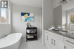 Full bath featuring a freestanding bath, vanity, and light marble finish flooring -