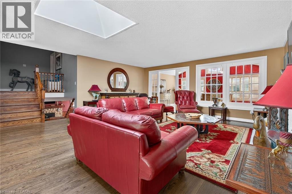 Living area featuring a skylight, wood finished floors, a textured ceiling, and stairway - 5590 Blind Line, Burlington, ON - Indoor Photo Showing Living Room