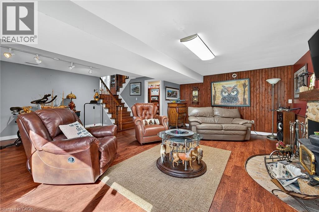 Living area featuring wood walls, wood finished floors, stairway, rail lighting, and a wood stove - 5590 Blind Line, Burlington, ON - Indoor Photo Showing Living Room