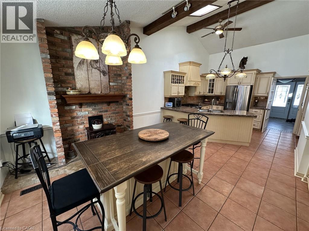 Dining space featuring a chandelier, a textured ceiling, a ceiling fan, light tile patterned floors, and high vaulted ceiling - 5590 Blind Line, Burlington, ON - Indoor Photo Showing Dining Room With Fireplace