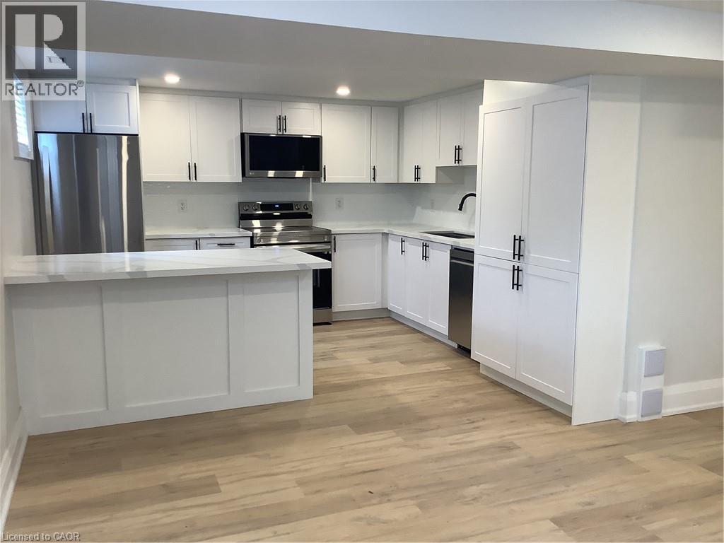 Kitchen with freestanding refrigerator, white cabinetry, range, light wood finished floors, and recessed lighting - 229 West 18Th Street, Hamilton, ON - Indoor Photo Showing Kitchen