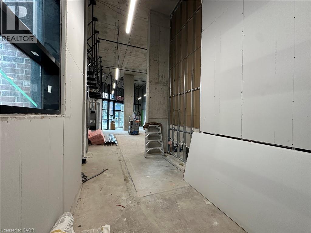 Corridor featuring unfinished concrete floors - 206 King Street W, Hamilton, ON