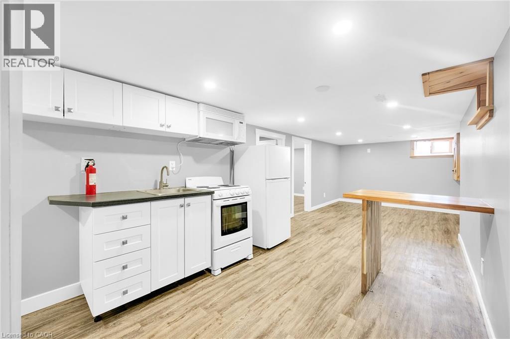 Kitchen with white appliances, a sink, baseboards, and recessed lighting - 129 Dundurn Street N, Hamilton, ON - Indoor