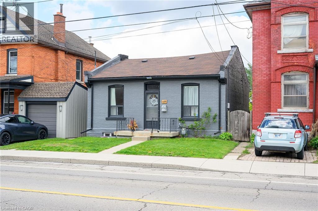View of front of house featuring brick siding, a gate, a garage, a front lawn, and roof with shingles - 129 Dundurn Street N, Hamilton, ON - Outdoor