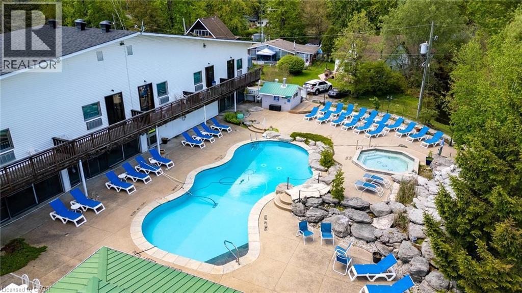 Community pool with a patio area, outdoor dining area, and view of scattered trees - 57 12Th Conc Road E Unit# 430, Flamborough, ON - Outdoor With In Ground Pool With Deck Patio Veranda