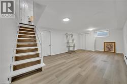 Basement with light wood-type flooring and stairs -
