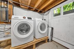 Laundry room featuring electric panel, separate washer and dryer, and concrete flooring -