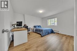 Bedroom featuring baseboard heating, light wood-style flooring, and a desk -