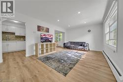 Living room featuring a baseboard heating unit, light wood-style floors, and recessed lighting -