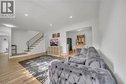 Living room with stairs, light wood-style flooring, and recessed lighting -