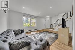 Living area with stairway, baseboard heating, light wood-style floors, and recessed lighting -