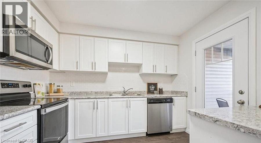 Kitchen featuring stainless steel appliances, white cabinets, and dark wood finished floors - 24 Morrison Road Unit# D9, Kitchener, ON - Indoor Photo Showing Kitchen With Upgraded Kitchen