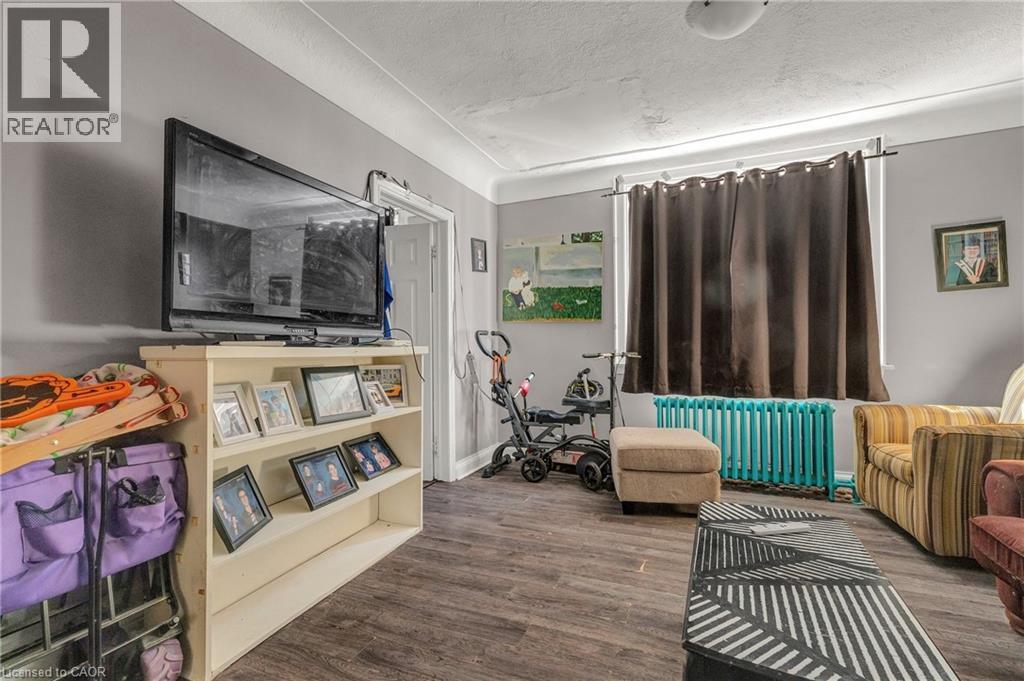 Living area with radiator heating unit, wood finished floors, and a textured ceiling - 70 Ottawa Street N, Hamilton, ON - Indoor Photo Showing Living Room