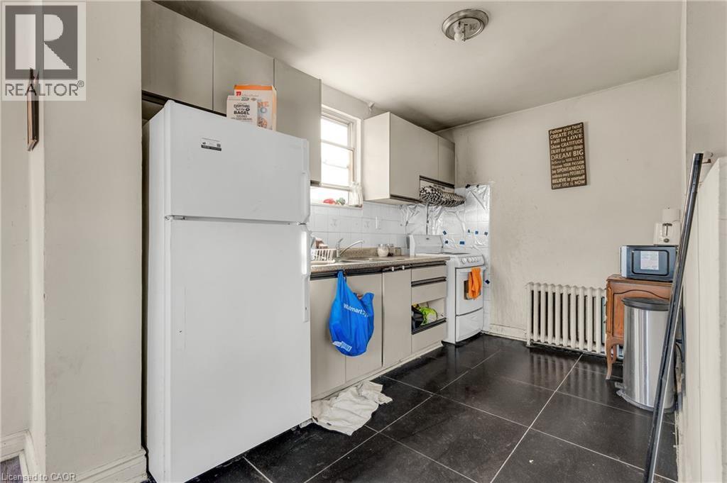 Kitchen featuring white appliances, radiator heating unit, white cabinets, tasteful backsplash, and exhaust hood - 70 Ottawa Street N, Hamilton, ON - Indoor