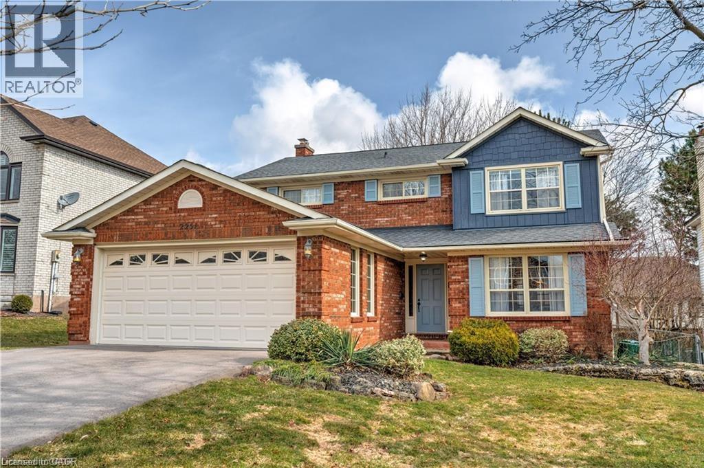 View of front of house with driveway, a front lawn, board and batten siding, a chimney, and a garage - 2251 Mansfield Drive, Burlington, ON - Outdoor With Facade