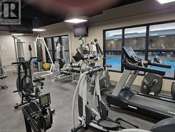 Fitness center featuring a variety of exercise equipment, dark-framed windows, recessed lighting, wall-mounted monitors, and a rubberized flooring surface -