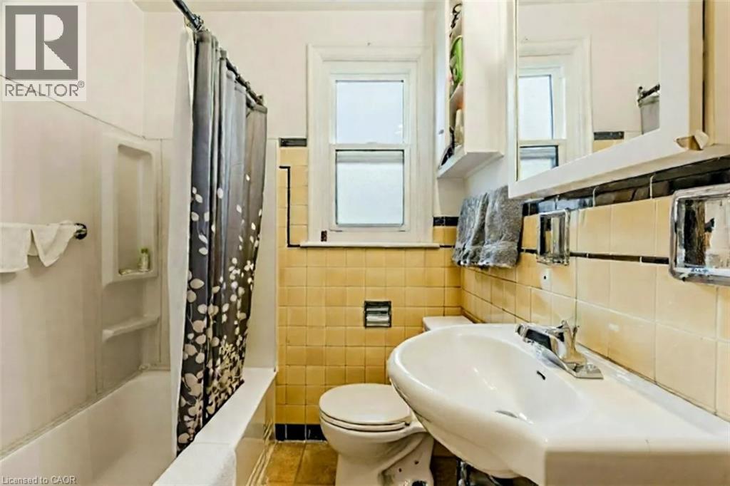 Full bath with shower / bath combo, tile walls, light tile patterned floors, and tasteful backsplash - 172 Markland Street, Hamilton, ON - Indoor Photo Showing Bathroom