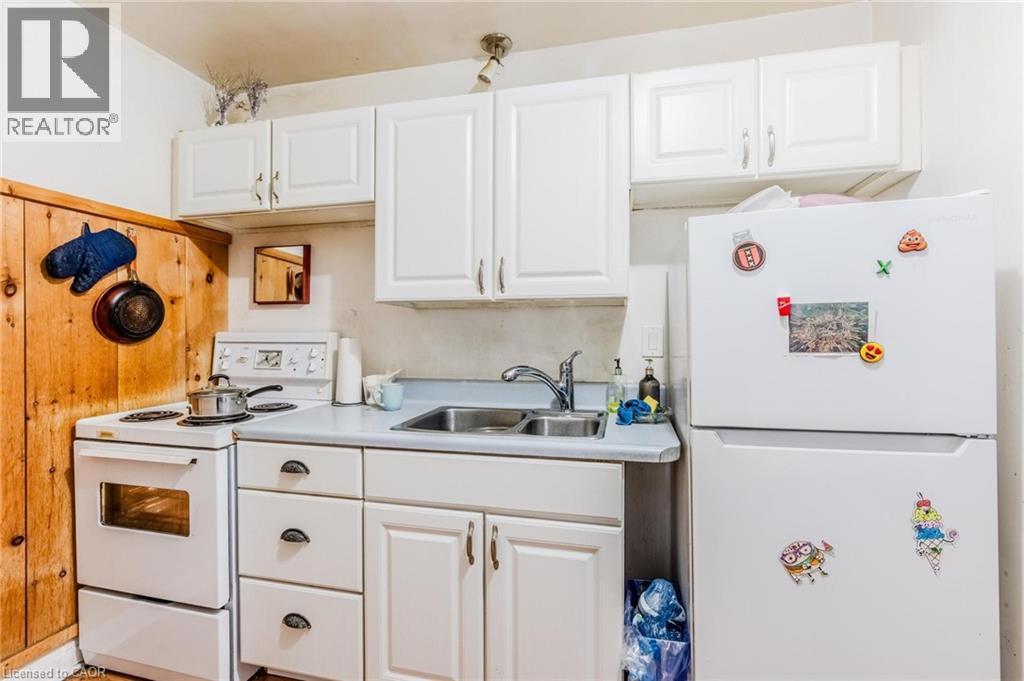 Kitchen with white appliances, white cabinets, and light countertops - 172 Markland Street, Hamilton, ON - Indoor Photo Showing Kitchen With Double Sink