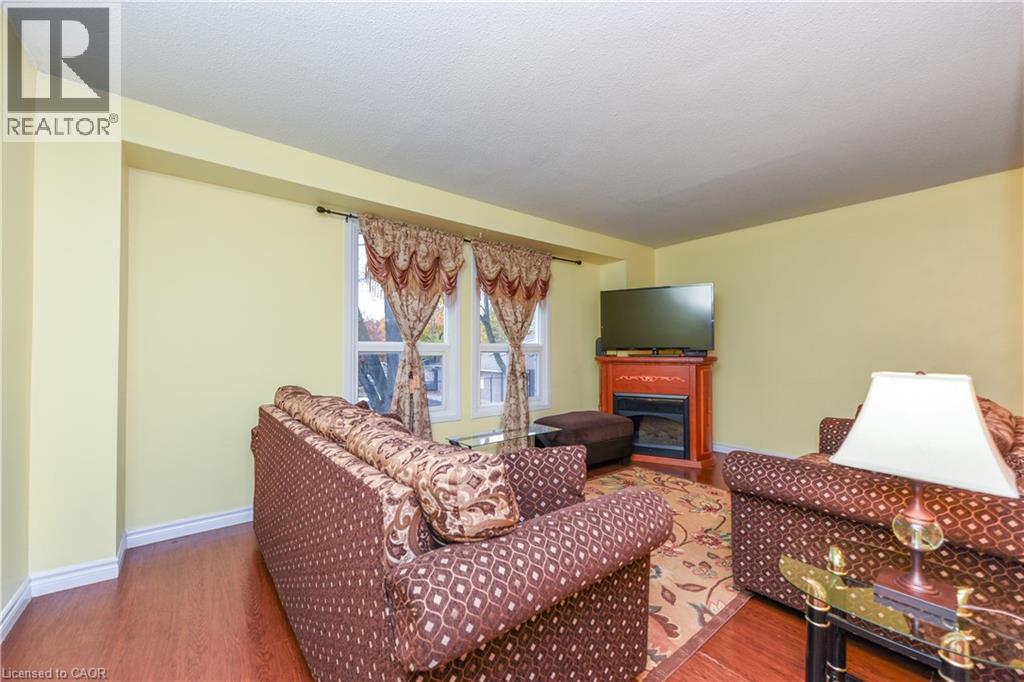 Living area with wood finished floors, a fireplace, and a textured ceiling - 85 Enmount Drive, Brampton, ON - Indoor With Fireplace