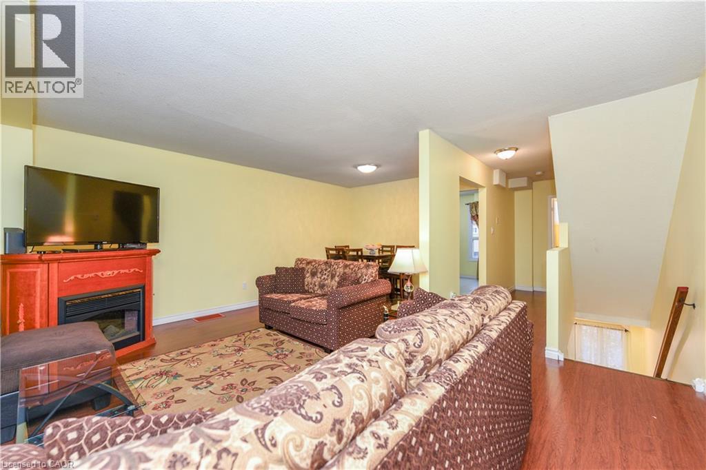 Living room with wood finished floors, a glass covered fireplace, and a textured ceiling - 85 Enmount Drive, Brampton, ON - Indoor Photo Showing Living Room With Fireplace