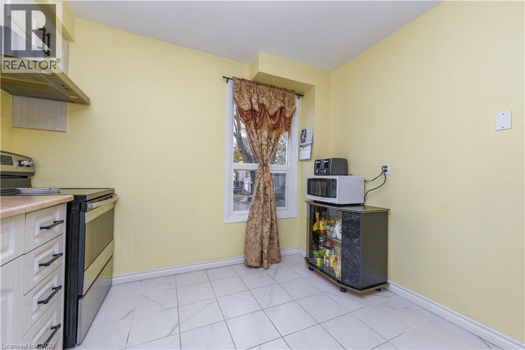Kitchen featuring electric stove, under cabinet range hood, white microwave, light countertops, and white cabinetry - 85 Enmount Drive, Brampton, ON - Indoor Photo Showing Kitchen