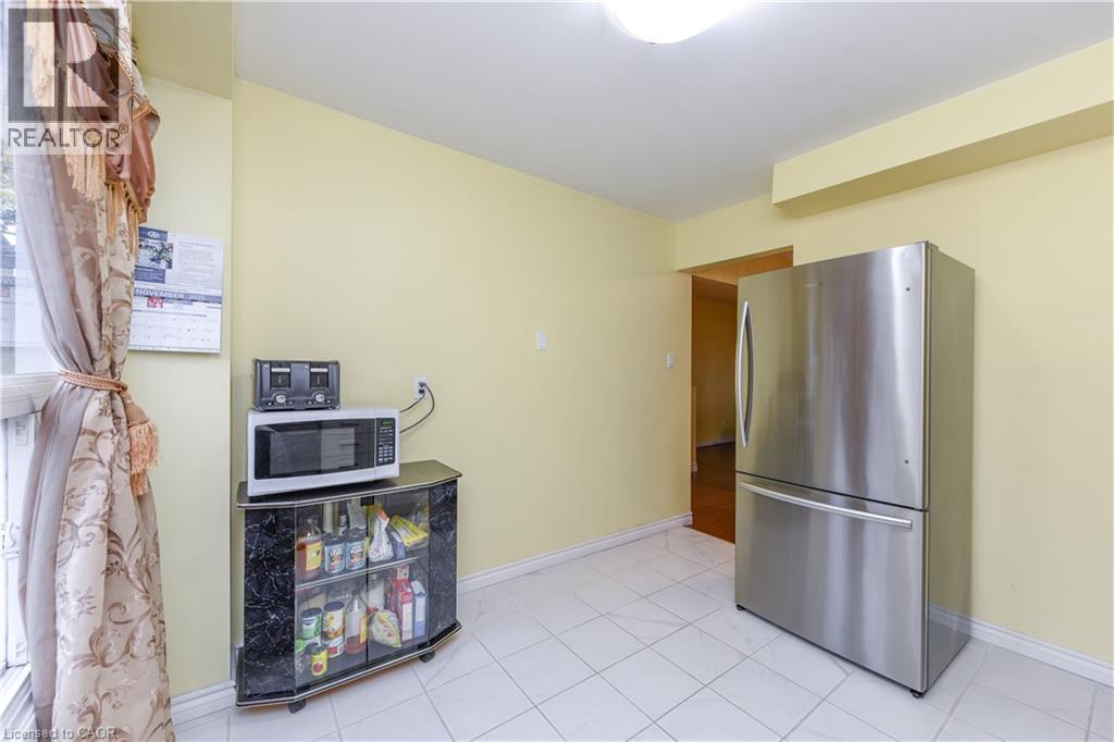 Kitchen featuring freestanding refrigerator, white microwave, and light tile patterned floors - 85 Enmount Drive, Brampton, ON - Indoor Photo Showing Other Room