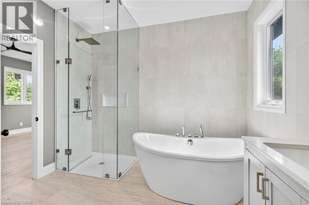 Full bathroom with a stall shower, a freestanding tub, vanity, and tile walls - 4006 Flemish Drive, Burlington, ON - Indoor Photo Showing Bathroom