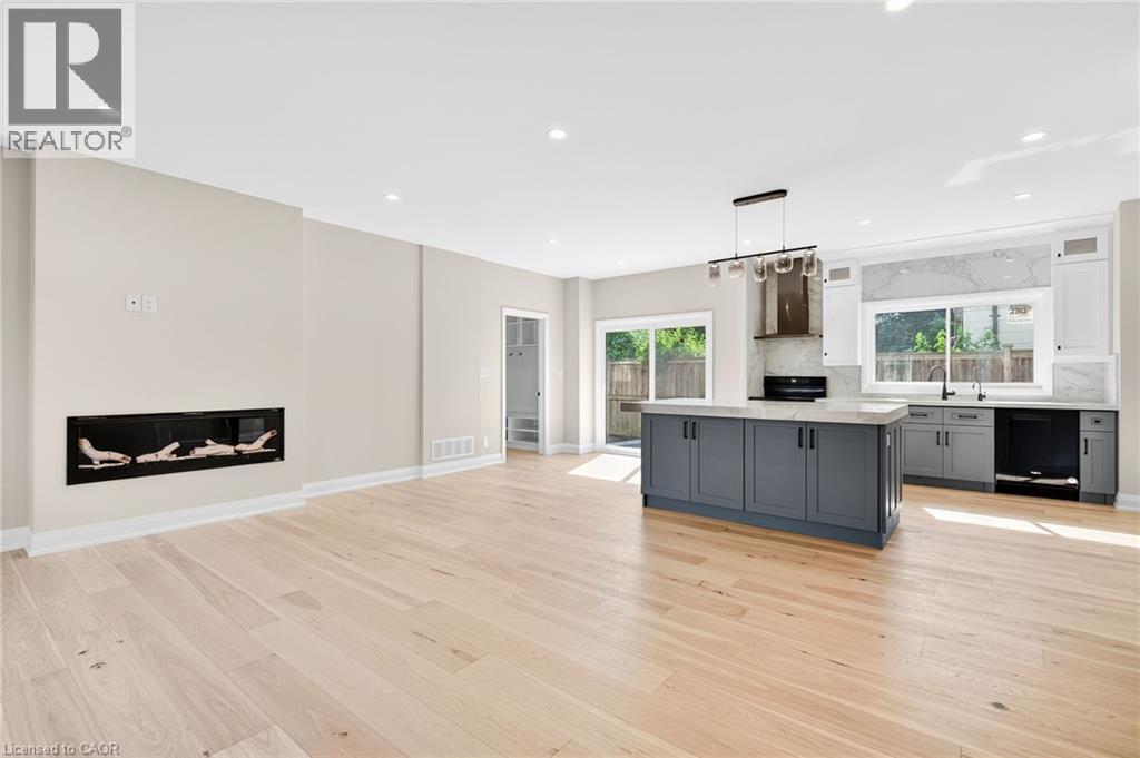 Kitchen featuring gray cabinetry, decorative light fixtures, a glass covered fireplace, plenty of natural light, and recessed lighting - 4006 Flemish Drive, Burlington, ON - Indoor