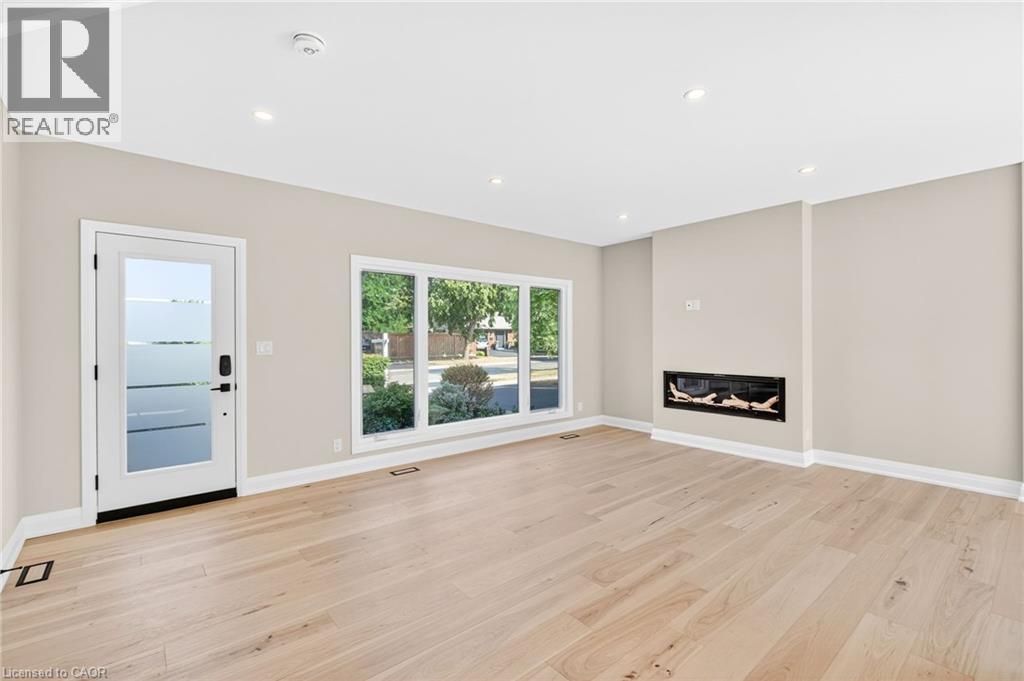 Unfurnished living room with a glass covered fireplace, light wood-style flooring, and recessed lighting - 4006 Flemish Drive, Burlington, ON - Indoor With Fireplace