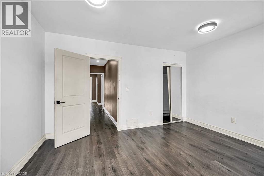 Unfurnished bedroom featuring dark wood-style flooring and baseboards - 334 Cannon Street E, Hamilton, ON - Indoor Photo Showing Other Room