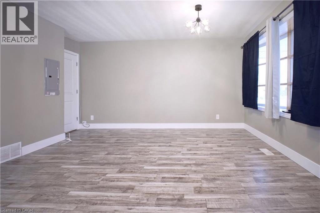 Empty room with light wood-style floors, electric panel, and a chandelier - 61 Bosworth Crescent, Kitchener, ON - Indoor Photo Showing Other Room