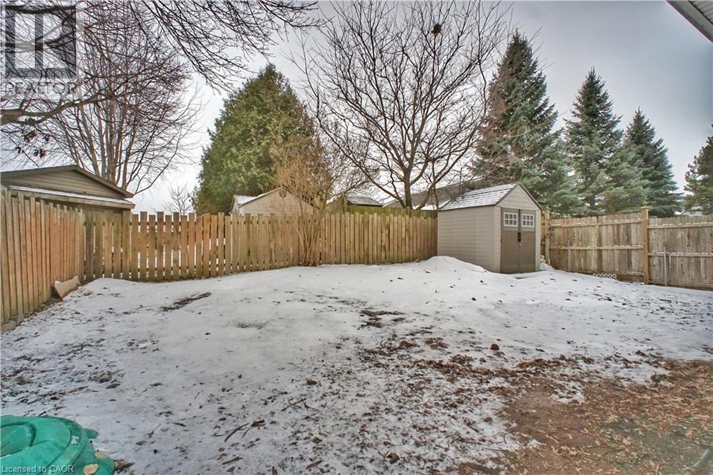 Yard covered in snow featuring a fenced backyard and a storage unit - 61 Bosworth Crescent, Kitchener, ON - Outdoor