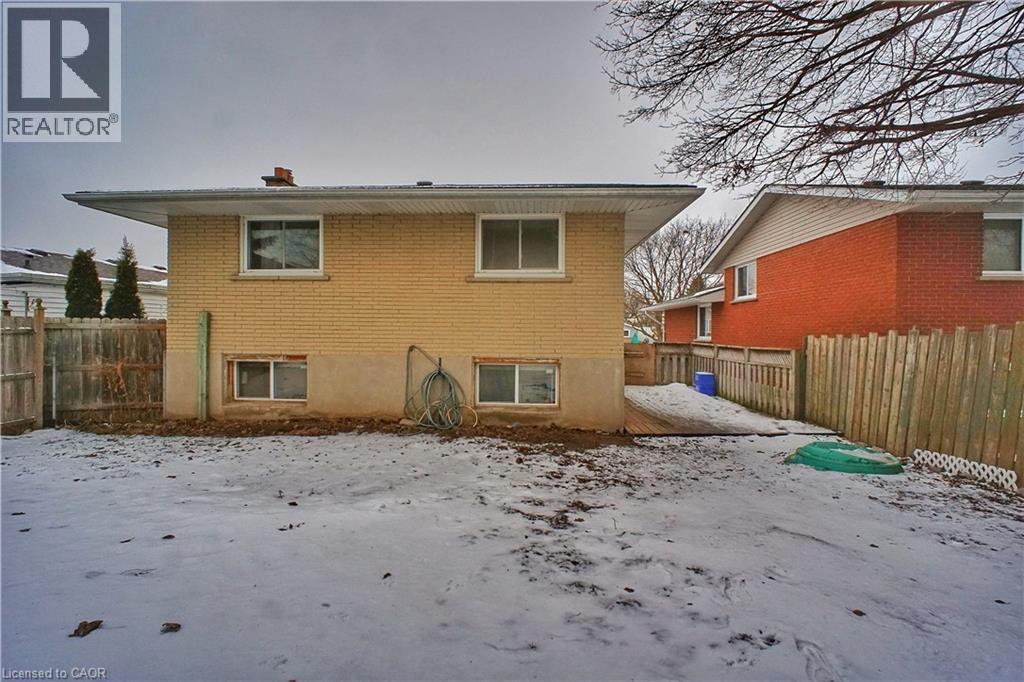 Snow covered back of property with a fenced backyard, brick siding, and a chimney - 61 Bosworth Crescent, Kitchener, ON - Outdoor With Exterior