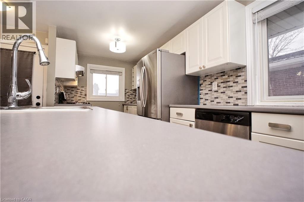 Kitchen with white cabinets, backsplash, appliances with stainless steel finishes, and light countertops - 61 Bosworth Crescent, Kitchener, ON - Indoor Photo Showing Kitchen