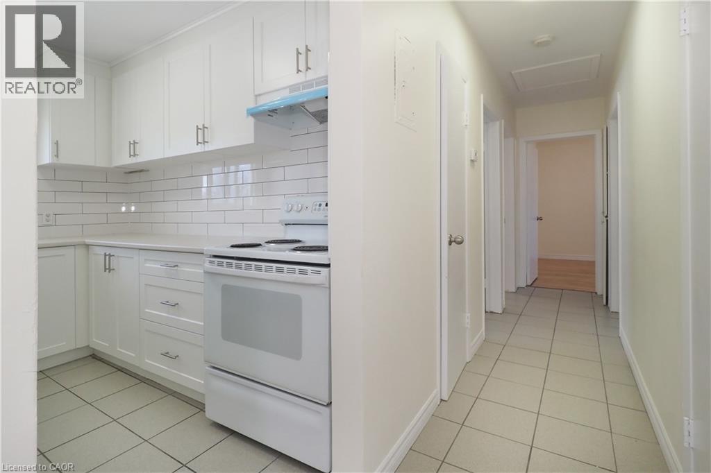Kitchen with white range with electric cooktop, white cabinets, light tile patterned floors, and tasteful backsplash - 24 Austin Drive, Waterloo, ON - Indoor Photo Showing Kitchen