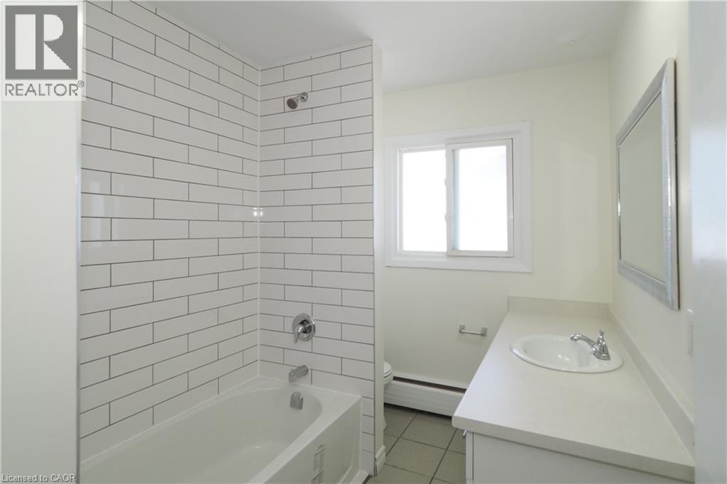 Bathroom with tub / shower combination, vanity, a baseboard heating unit, and light tile patterned floors - 24 Austin Drive, Waterloo, ON - Indoor Photo Showing Bathroom