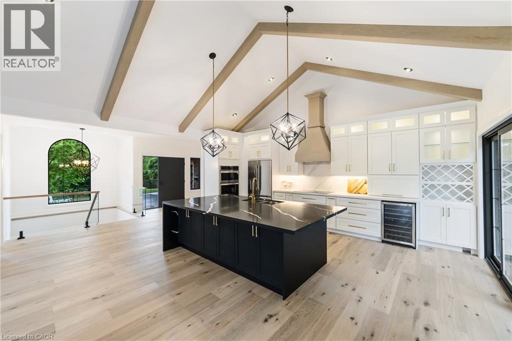 Kitchen with all new stainless steel appliances, custom white cabinetry with additional cabinets in island, induction stove top, luxury flooring, garden doors to the right, beam ceiling, display cabin - 515 Hamilton Drive, Ancaster, ON - Indoor Photo Showing Kitchen With Upgraded Kitchen