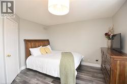 Bedroom with dark wood-style flooring and baseboards -