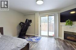 Bedroom with a premium fireplace, light wood finished floors, and access to exterior -