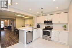 Kitchen featuring stainless steel appliances, light marble finish flooring, white cabinetry, and recessed lighting -