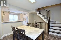 Dining area with dark wood-style flooring and stairway -