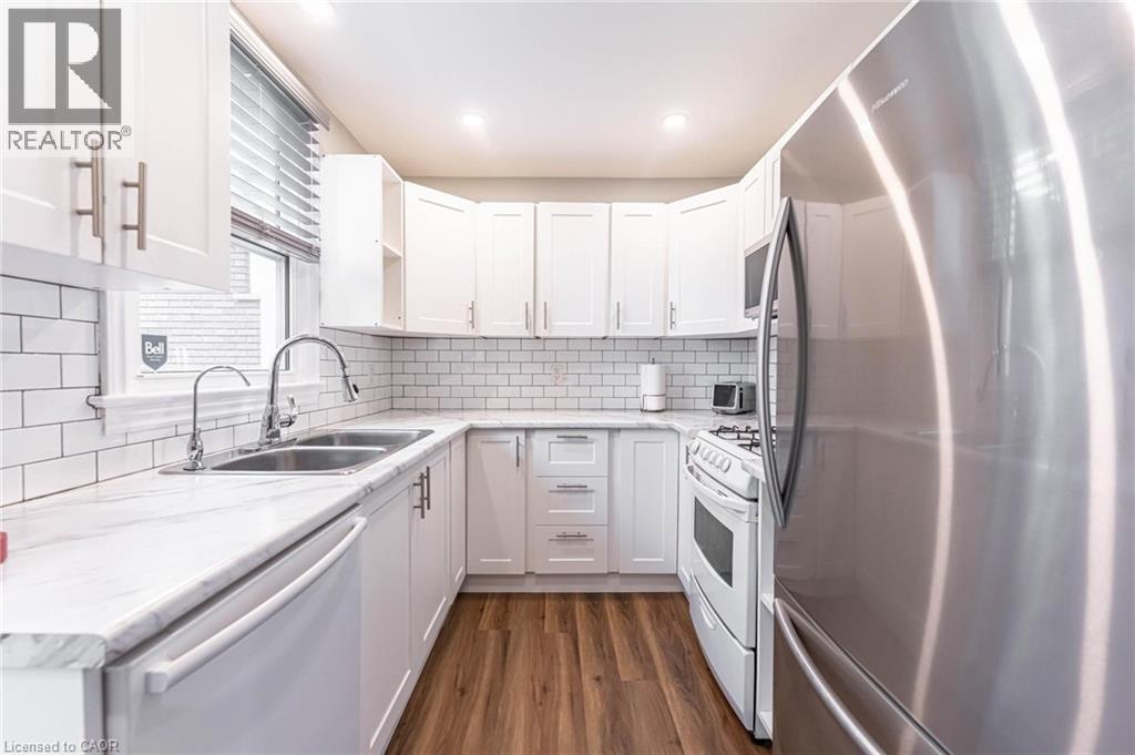 Kitchen with stainless steel appliances, white cabinetry, dark wood finished floors, light stone countertops, and recessed lighting - 140 Royal Avenue, Hamilton, ON - Indoor Photo Showing Kitchen With Double Sink With Upgraded Kitchen