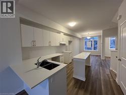 Kitchen featuring white cabinetry, dark wood finished floors, a breakfast bar area, a kitchen island, and light stone countertops -
